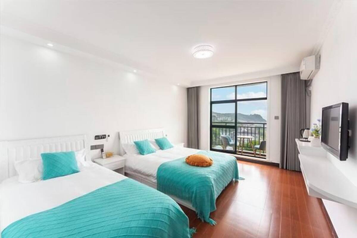 Une chambre d’hôtel avec deux lits, un balcon offrant une vue agréable, une télévision à écran plat et un design moderne.