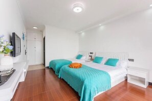 A hotel room with two beds, white walls, and a wooden floor.