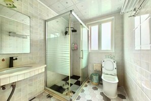 A modern bathroom with a glass shower enclosure, a toilet, and a sink with a mirror.