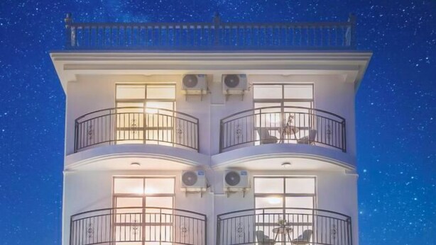 Un edificio de varios pisos con balcones y unidades de aire acondicionado, bajo un cielo nocturno lleno de estrellas.