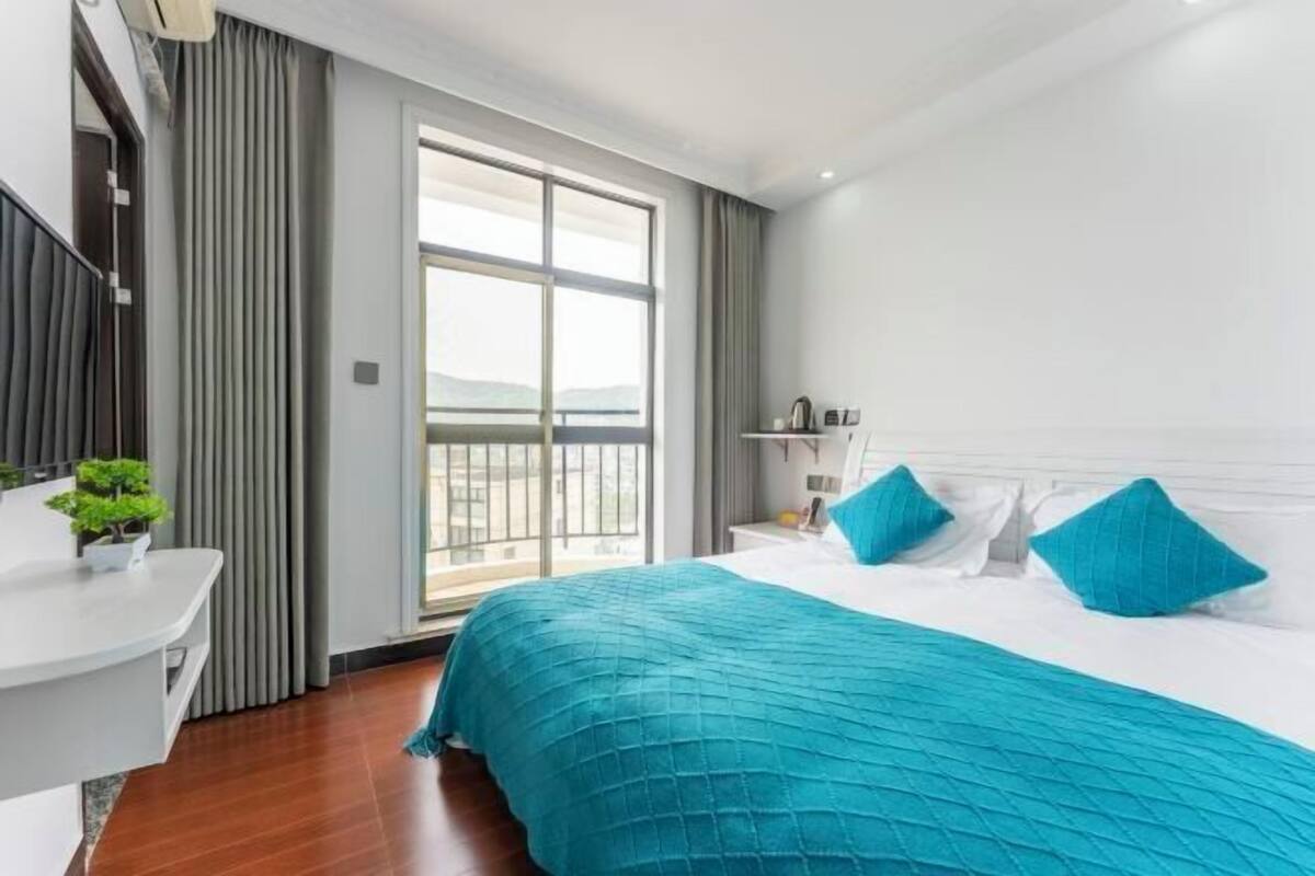 Une chambre d’hôtel avec un grand lit, un bureau, une fenêtre avec des rideaux et une vue sur l’extérieur.