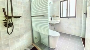 Un baño con cabina de ducha de vidrio, inodoro y lavamanos.