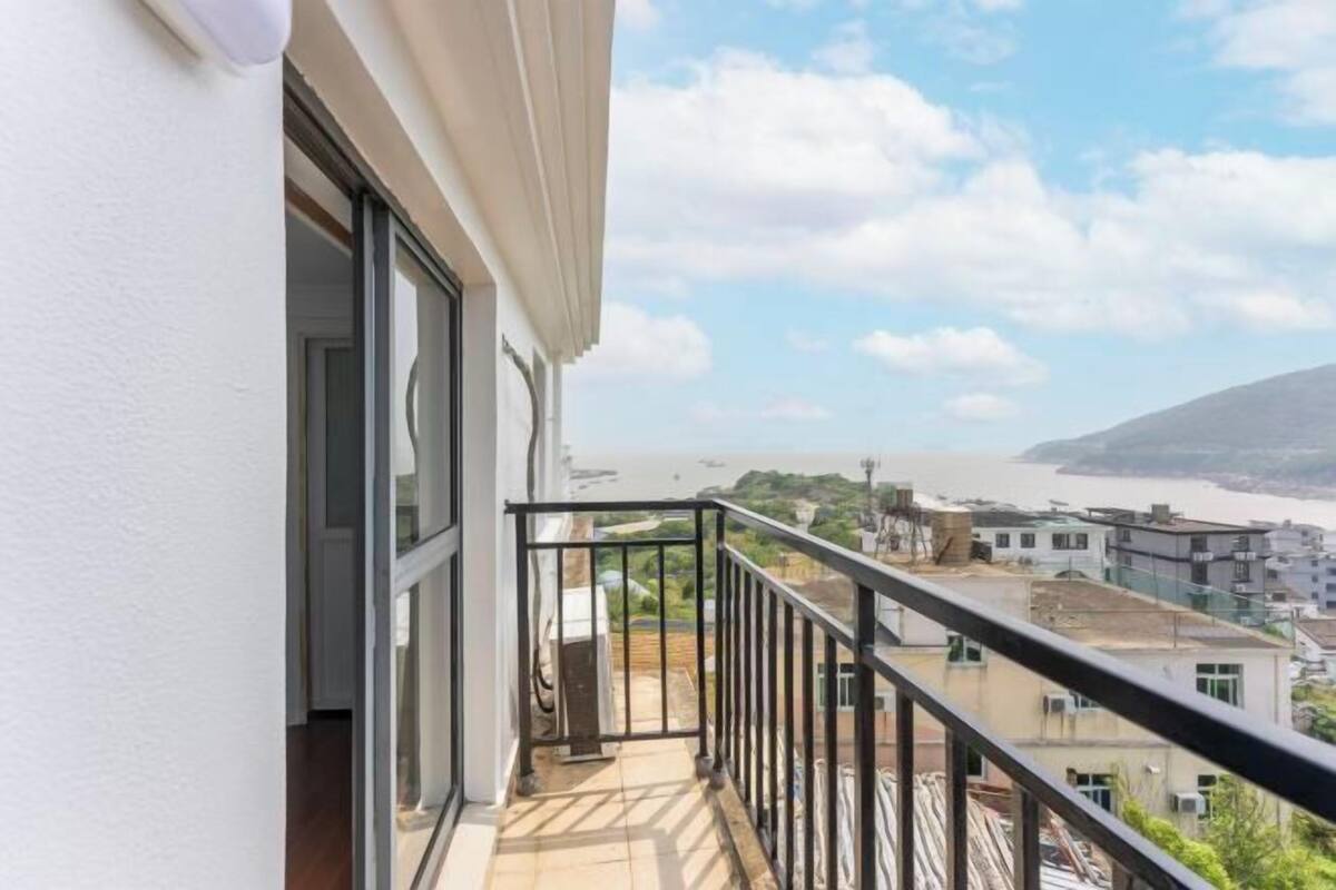 Un balcon offrant une vue sur un paysage urbain côtier et sur une étendue d’eau.