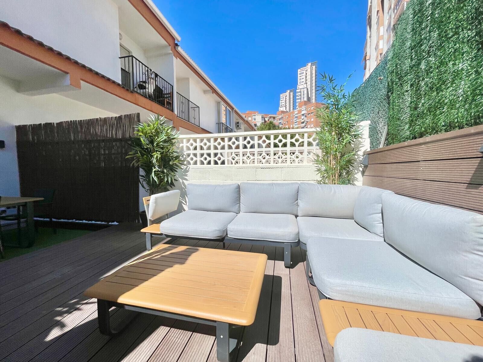 Eine Terrasse mit einem Holztisch und einer grauen Sofagarnitur.