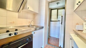 A compact kitchen with a stainless steel range hood, a built-in oven, and a sink.