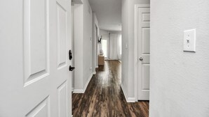 Un pasillo con puertas blancas y suelo de madera.