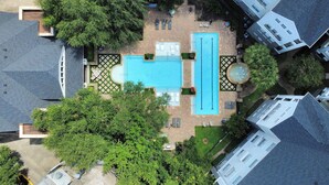 Vista aérea de una zona residencial con piscina, sillas de descanso y una fuente.