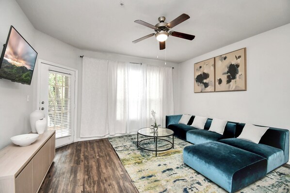 A modern living room with a blue sofa, a round coffee table, and a ceiling fan.