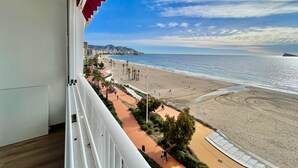A balcony with a view of a beach, a cityscape, and a clear sky.