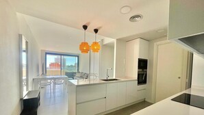 A modern kitchen with white cabinetry, a central island, and a built-in oven. - LUXURY BENIDORM BEACH PONIENTE N107 (Benidorm)