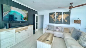 A modern living room with a large flat-screen TV, a wooden coffee table, a beige sofa, and a ceiling fan. - EMALCO SEAFRONT MODERN APARTMENT A061 (Benidorm)