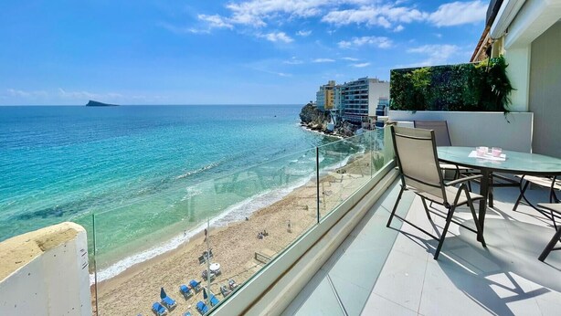 A balcony with a clear view of a beach and ocean, a dining table with chairs, and a glass railing. - EMALCO SEAFRONT MODERN APARTMENT A061 (Benidorm)