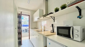 A modern kitchen with white cabinets, a microwave, and a sink.