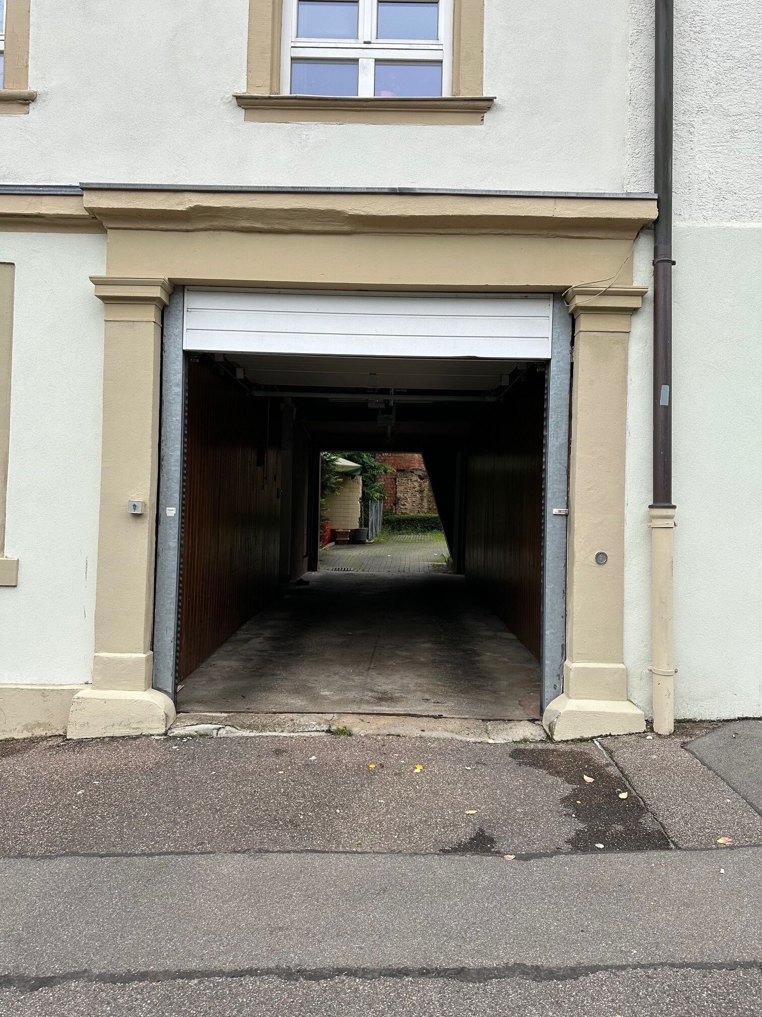 A garage entrance with a closed garage door, a concrete driveway, and a brick wall in the background.