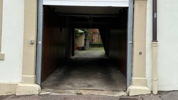 A garage entrance with a closed garage door, a concrete driveway, and a brick wall in the background.