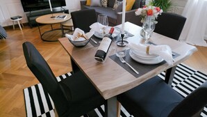 Ein Essbereich mit Tisch für zwei Personen, einer Weinflasche und einem Blumenstrauß.