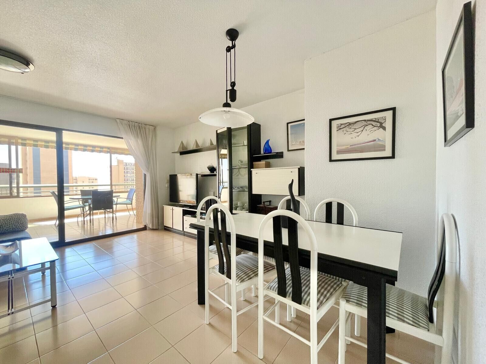 Ein modernes Wohnzimmer mit Essbereich, großen Fenstern und einem Balkon.