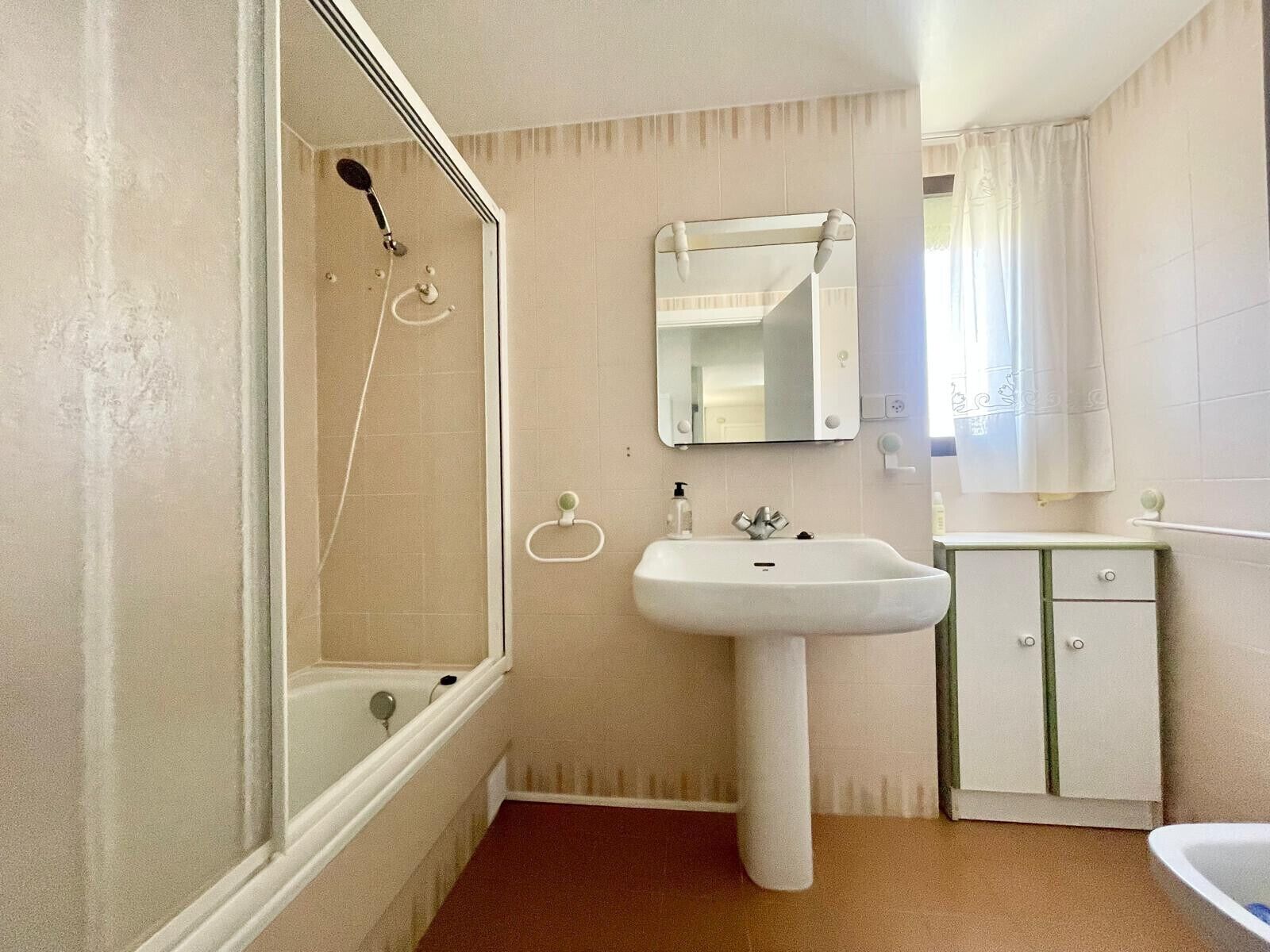 Een badkamer met een bad, een wastafel, een spiegel en een kast.