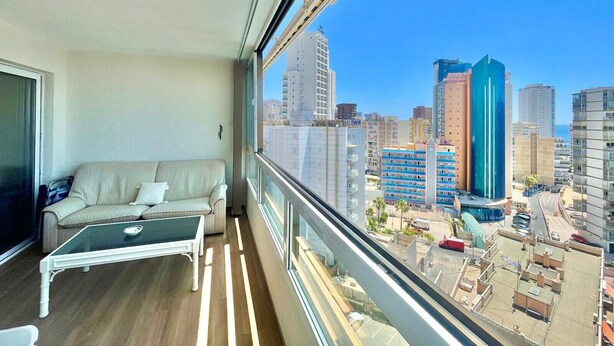 A balcony with a sofa and a glass table, overlooking a cityscape with modern buildings. - ALBAIDA PARK BENIDORM LEVANTE (A137) (Benidorm)
