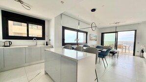 Une cuisine moderne avec un îlot central, un coin repas avec une table et des chaises, et un balcon avec vue.