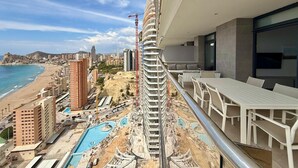 Un immeuble de grande hauteur doté d’un balcon donnant sur une plage et une piscine.