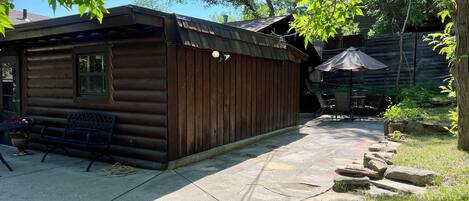 Een houten hut met een terras, een bank en een tafel met stoelen.