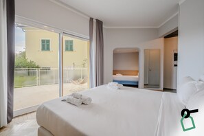 Ein Hotelzimmer mit Bett, einem Balkon und einer Tür zu einem anderen Raum.