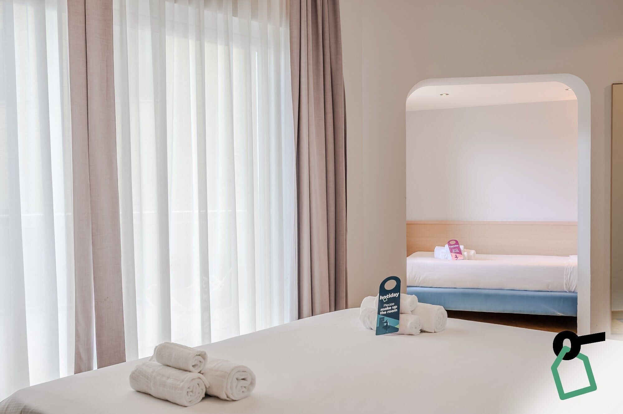 Ein Hotelzimmer mit einem Bett, einem Spiegel und einem Schild auf dem Bett.