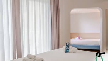Ein Hotelzimmer mit einem Bett, einem Spiegel und einem Schild auf dem Bett.