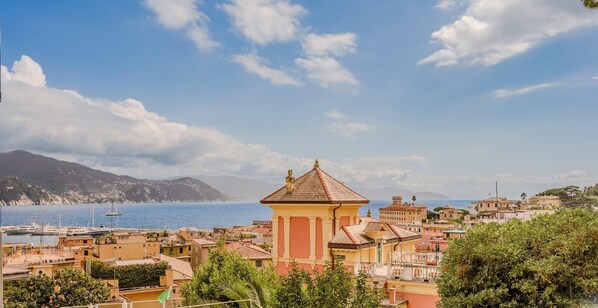 A coastal town with a prominent tower, buildings with red roofs, and a clear view of the sea and distant mountains. - Hotiday Santa Margherita Porto (Santa Margherita Ligure)