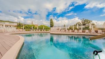Una piscina al aire libre de temporada, sombrillas