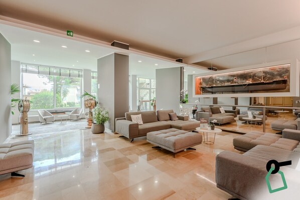 A spacious lobby with a large seating area, a modern art piece, and large windows offering a view of the outdoors. - Hotiday Santa Margherita Porto (Santa Margherita Ligure)