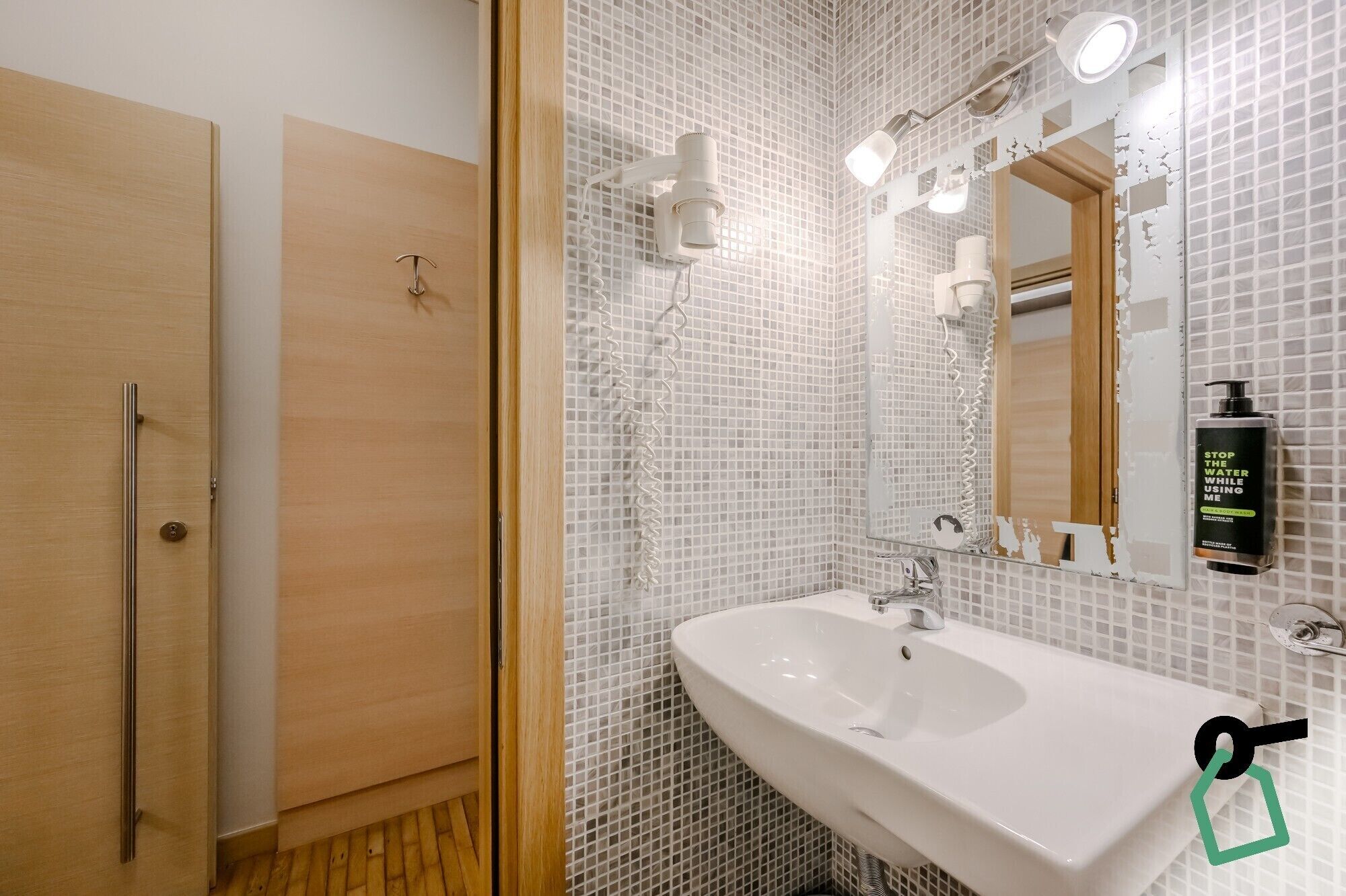 Une salle de bain avec un lavabo blanc, un miroir et une douche.