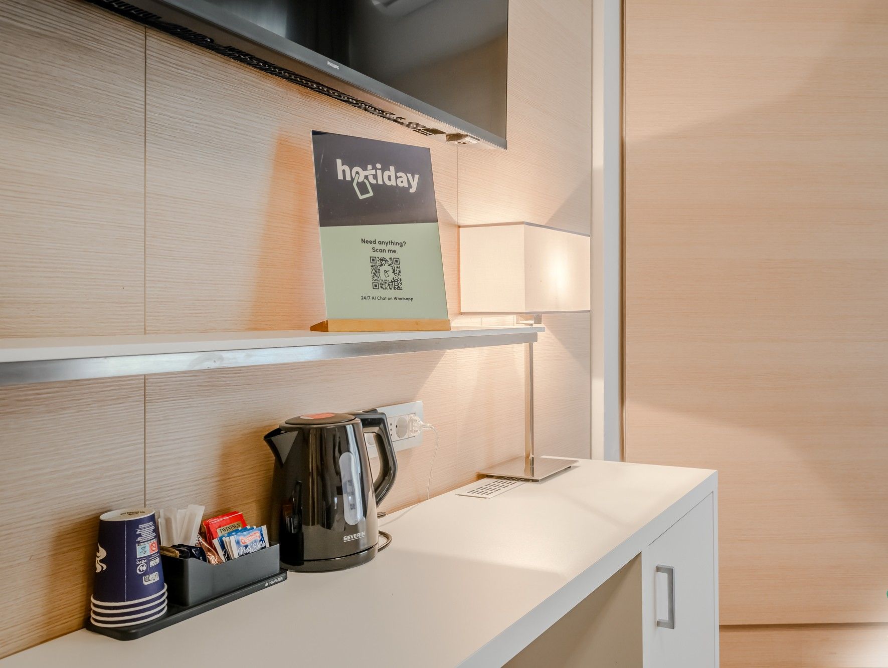 Ein Hotel-Rezeptionsbereich mit einem Schild mit der Aufschrift 'holiday', einem Wasserkocher, einer Kaffeemaschine und einem Laptop auf der Theke.