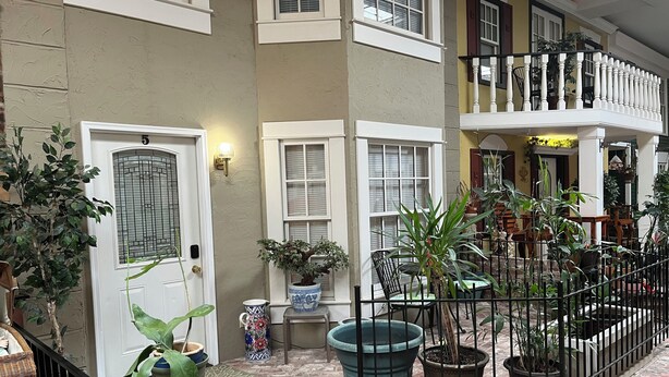 A multi-level residential building with a brick patio, potted plants, and a balcony with a railing. - #05 Charming 2-bedroom apartment in Lorain with AC, WiFi (Lorain)