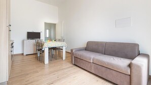 Ein modernes Wohnzimmer mit einer Couch, einem Esstisch mit Stühlen und einem Fernseher.