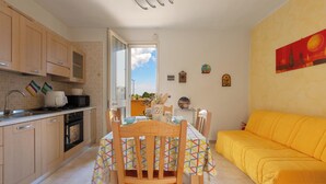 Eine Küche mit Holzschränken, einem Esstisch mit bunten Tischdecken und einem gelben Sofa.