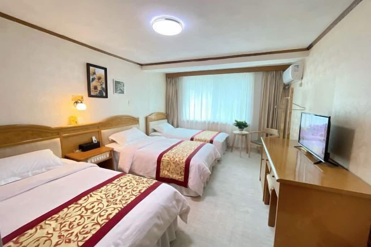 A hotel room with two beds, a TV, a desk, and a small table.