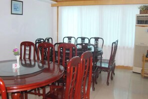 Un coin repas avec une table ronde, plusieurs chaises et une grande fenêtre avec des rideaux.