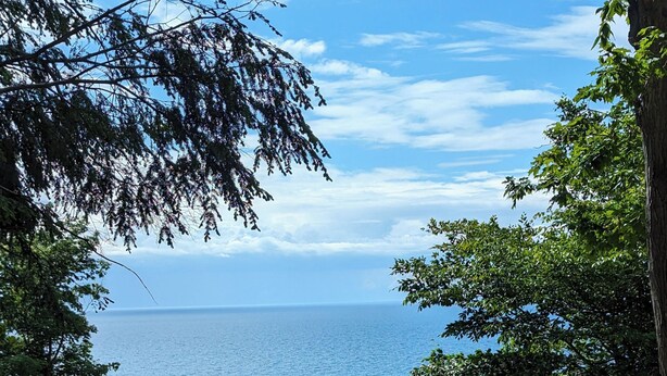 Ein Schotterweg führt zu einem dunkel gefärbten Haus mit Blick auf das Meer.