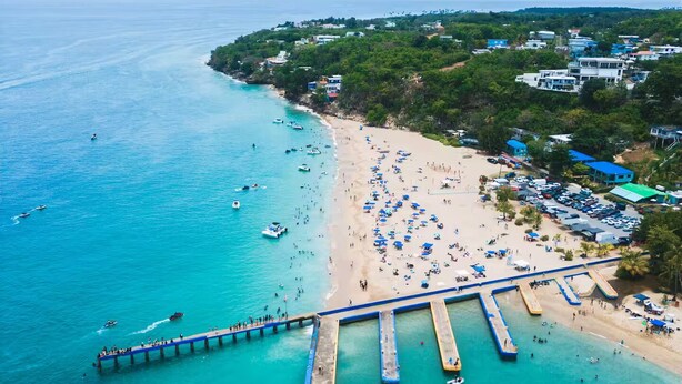 An aerial view of a beach with a pier extending into the water, surrounded by a coastal town. - Home for 15 Guests with Private Pool and Pool Table (Aguadilla)