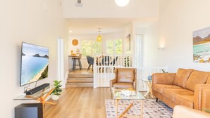 A living room with a TV, sofa, coffee table, and a dining area with chairs and a table. - Tomaree Mews 5, 18 Tomaree St - Stunning townhouse in the heart of town (Nelson Bay)