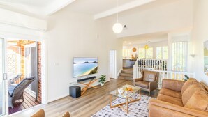 A spacious living area with a large TV, a glass coffee table, and a comfortable seating arrangement. - Tomaree Mews 5, 18 Tomaree St - Stunning townhouse in the heart of town (Nelson Bay)