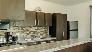 Une cuisine moderne avec des meubles en bois foncé, un réfrigérateur en acier inoxydable, un pare-feu en carrelage et un plan de travail en marbre.