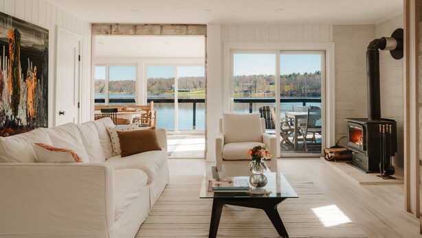 A spacious living room with a white sofa, a glass coffee table, and a fireplace.