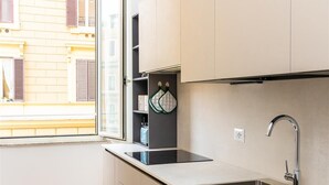 A modern kitchen with a stainless steel sink, a window, and a view of a yellow building. - Cola di Rienzo apartment (Rome)