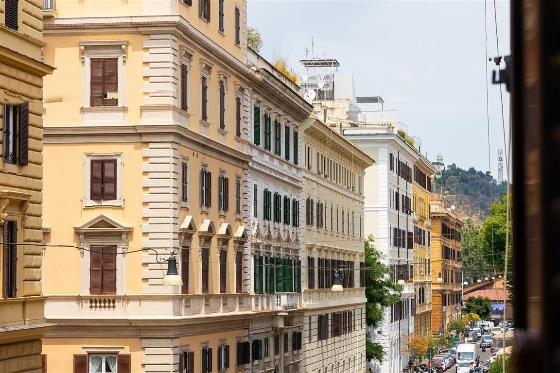 A multi-story building with classical architecture, featuring balconies and a street view.
