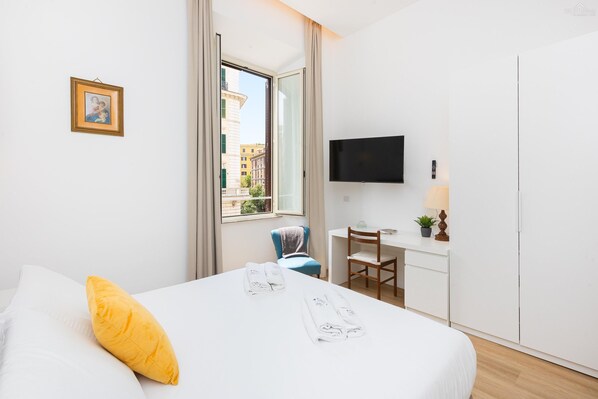 A modern hotel room with a bed, a desk, a chair, a TV, and a window with a city view. - Cola di Rienzo apartment (Rome)
