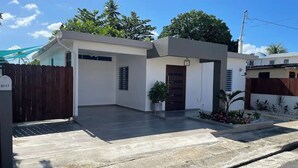 Une maison moderne à deux étages, dotée d’un toit plat, d’un porche à l’avant et d’une entrée sécurisée par un portail.