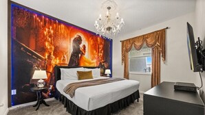Ein Schlafzimmer mit einem großen Bett, einer Kandelaber, einem Fernseher und einem Wandbild.